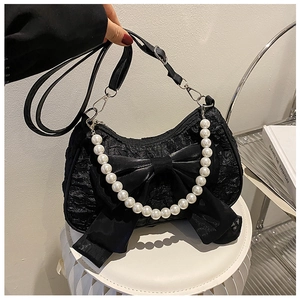 Detail of black pleated shoulder bag featuring a large bow and pearl handle ornament