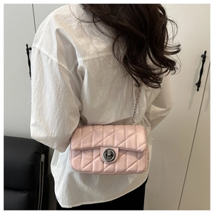 Détail d'un sac bandoulière matelassé rose avec fermoir argenté et chaîne en métal