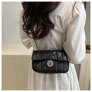 Détail du sac bandoulière matelassé noir avec chaîne argentée porté par le mannequin