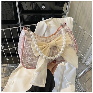 Detail of pink jacquard bag with oversized cream bow and elegant white pearl handle