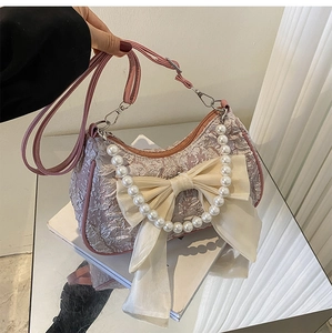 Close-up of pink pleated handbag featuring decorative silk bow and pearl handle beads