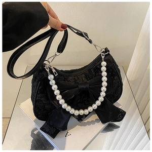 Detail of black bow and large pearl handle on textured floral embossed handbag