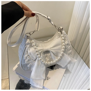 Detail of white pleated bag with large bow and elegant pearl handle for women