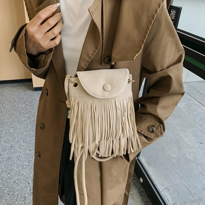 Beige suede tassel bucket bag with fringes and crossbody strap shown on a model