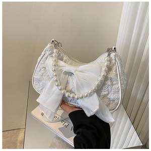 Detailed view of white pleated handbag featuring a mesh bow and elegant pearl handle