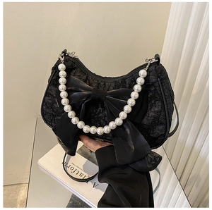 Detailed view of the black textured fabric bag with oversized bow and pearl handle
