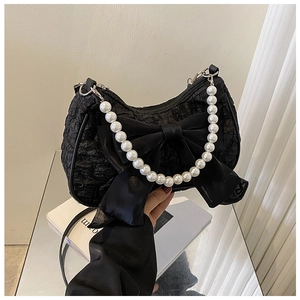 Close-up of black pleated handbag with satin bow and white imitation pearl handle