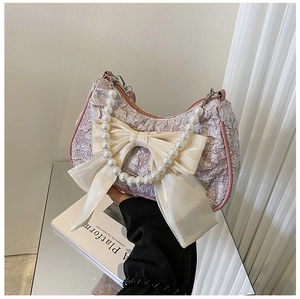 Detailed view of pink jacquard handbag featuring a large satin bow and pearl handle