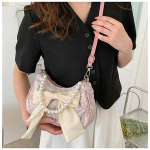 Detail of pink textured handbag featuring cream satin bow and pearl handle strap