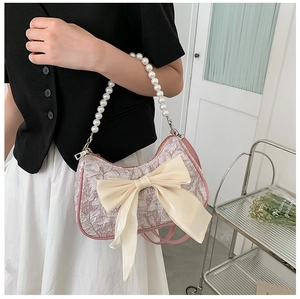 Detail of pink hobo bag with large silk bow and elegant imitation pearl handle strap