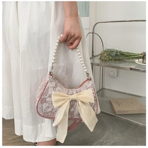Detail of pink jacquard handbag featuring a large chiffon bow and faux pearl handle