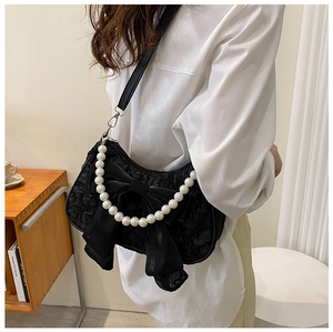 Detail of black lace crossbody bag featuring a large bow and white pearl handle