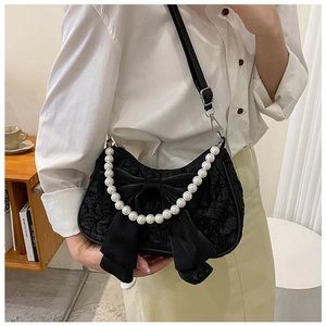 Detail of black pleated shoulder bag with large satin bow and decorative pearl handle