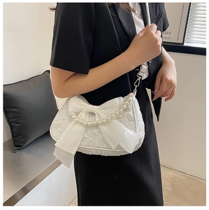 Detail of white textured shoulder bag with mesh bow and pearl chain decoration