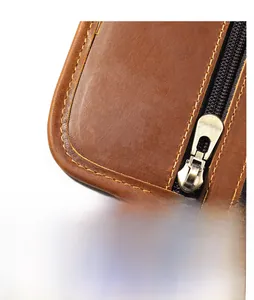 Detail of premium brown leather texture with precise yellow stitching and metal zipper