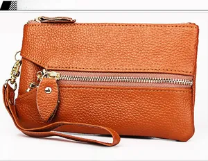 Close-up of caramel pebbled leather coin purse with golden zipper and wrist strap