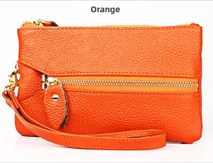Macro detail of orange pebble grain leather wallet with gold hardware and wrist strap