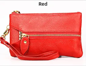 Detail of red pebbled leather coin purse with golden zipper and wrist strap feature