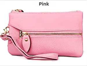 Detailed view of pink pebble grain leather wallet featuring gold zippers and wrist strap