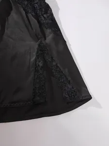 Détail de satin noir avec dentelle florale exquise sur la fente latérale du vêtement