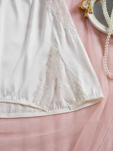 Détail de lingerie en satin blanc avec dentelle florale délicate et fente sur le côté