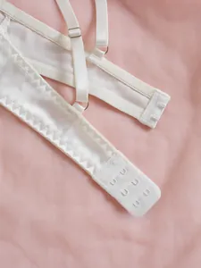 Détails de lingerie en satin blanc montrant les bretelles réglables et le fermoir au dos