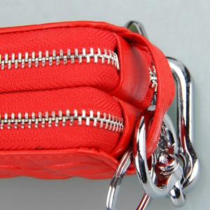 Detail of red quilted leather car key case featuring secure double zippers and silver hardware