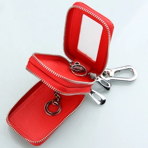 Red leather car key case detail showing dual zippers, internal rings and a clear window