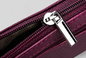 Detail of high-gloss silver metal zipper on purple lychee pattern leather coin purse