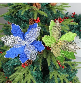 Détails de fleurs de Noël pailletées bleues et vertes sur sapin avec pommes de pin