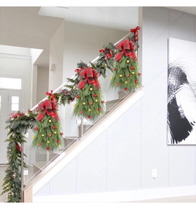 Detail van kersttrapversiering met groene dennennaalden, rode strikken en ornamenten