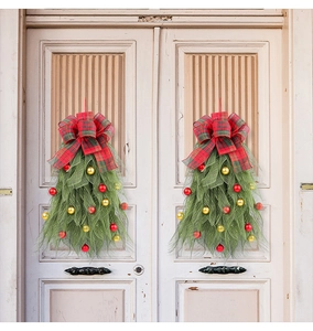 Detail van twee kerstslingers met geruite strikken en ornamenten op witte deuren