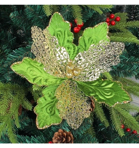 Détail d'une fleur de Noël verte et dorée pailletée sur sapin avec baies et pommes de pin