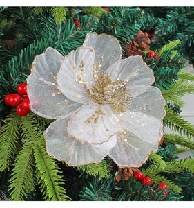 Detail of white mesh Christmas flower with gold glitter edges on green pine branch