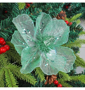Macro shot of mint green mesh Christmas flower with sequins on festive pine branches