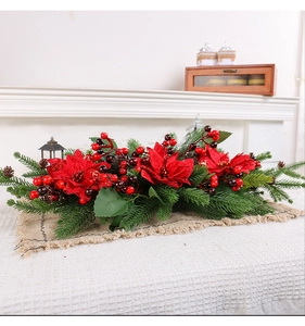 Detail of red poinsettia flowers with berries and pine cones on a rustic burlap runner