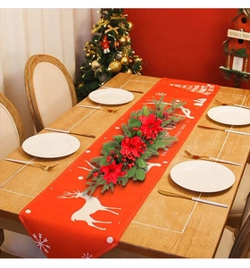 Close-up of Christmas table centerpiece with red poinsettias, pine needles and berries