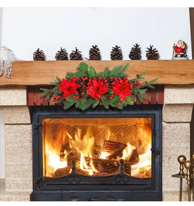 Close-up of a Christmas wreath with poinsettias and berries on a warm fireplace mantle