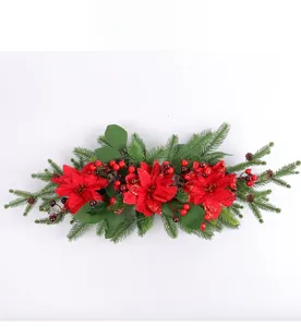 Detail of a Christmas swag featuring red poinsettias, green pine needles, and holly berries