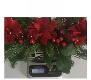 Detailed view of red Christmas poinsettia and berry wreath weighing 242 grams on a scale
