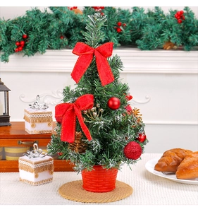 Vue détaillée du mini sapin de Noël de table avec nœuds rouges et aiguilles enneigées