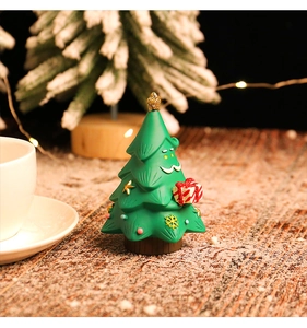 Primo piano di una statuetta a forma di albero di Natale in resina con un viso carino e dono