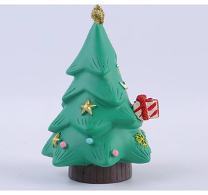 Dettaglio di statuetta a albero di Natale in resina con stelle dorate e regalo