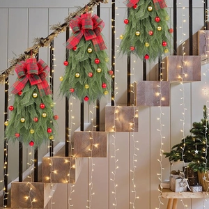 Kerst teardrop swag met rode geruite strik en ballen aan een moderne traphekje leuning