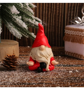 Detailed view of a sitting Christmas gnome figurine with red hat on snowy wood background