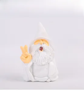 Détail d'un nain de jardin avec bonnet blanc et barbe faisant le signe de paix