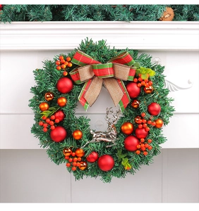 Detail of Christmas wreath with red berries, plaid bow and silver reindeer on fireplace