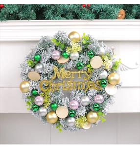 Close-up of frosted Christmas wreath with colorful baubles and golden Merry Christmas sign