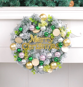 Detail view of snowy Christmas wreath with Merry Christmas sign and colorful baubles