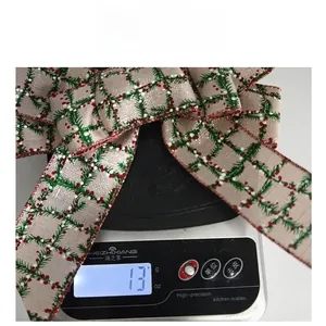 Detail view of a 13g Christmas linen bow with pine needle and berry print on a scale